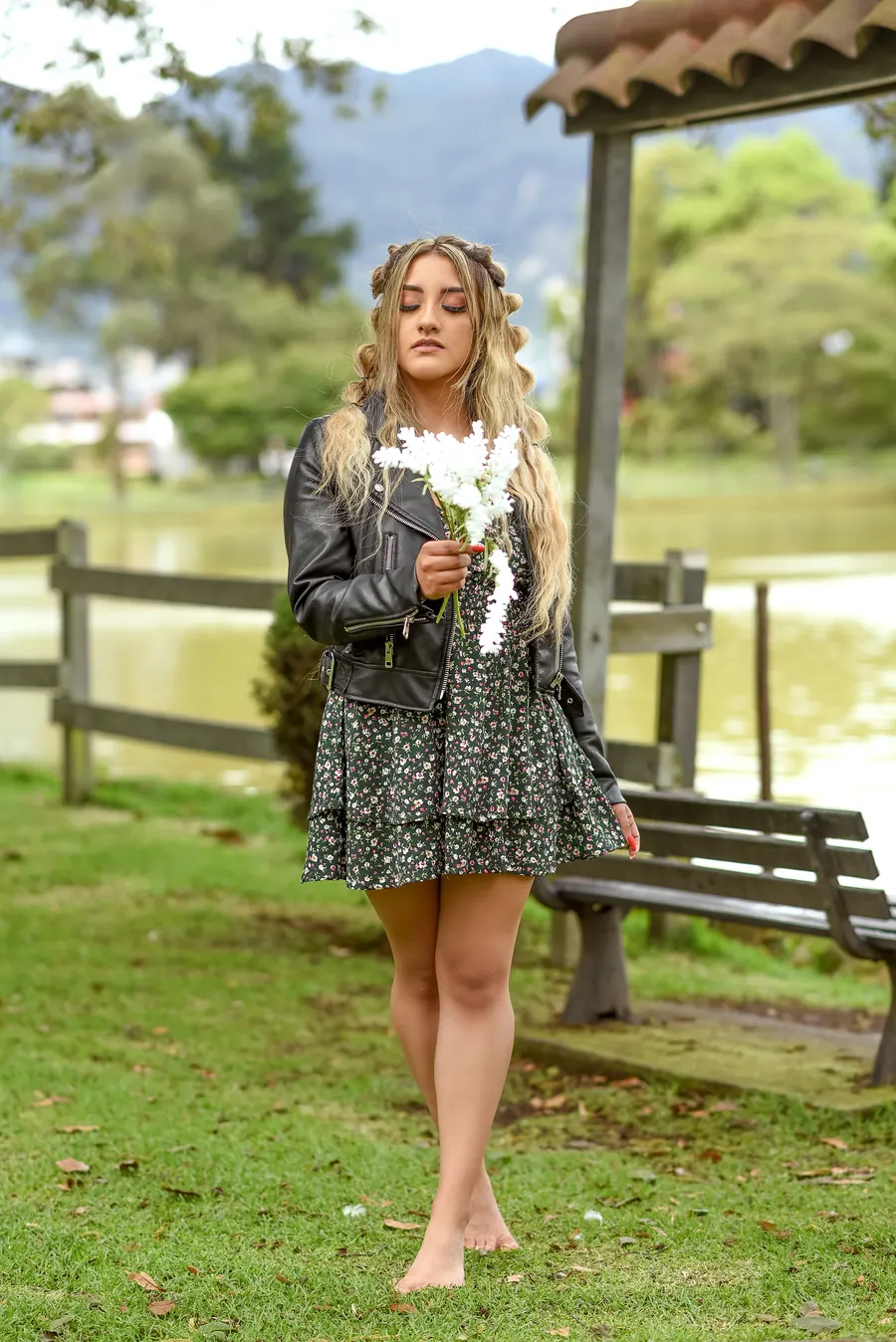 Modelo de Red Paradise VIP en una sesión de fotos al aire libre, caminando por un parque con vestido de flores y chaqueta